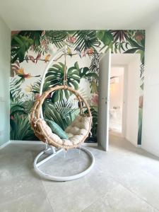 silla de mimbre en una habitación con papel pintado tropical en Bea Trees - Lake Garda, en Puegnago sul Garda