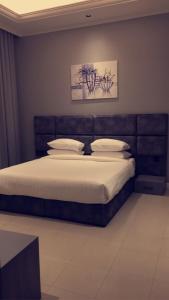 Voyage Apartments في الرياض: غرفة نوم بسرير كبير عليها شراشف ووسائد بيضاء