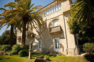 a building with a palm tree in front of it at Casa Grande la Almuiña in Arbo