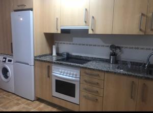 a kitchen with a stove and a white refrigerator at Apartamentos turísticos CHUS 2 in Corcubión