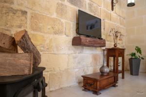 a living room with a tv on a stone wall at IL Gnejna II in Xagħra