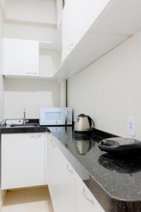 a kitchen with white cabinets and a black counter top at Pousada Meireles in Fortaleza