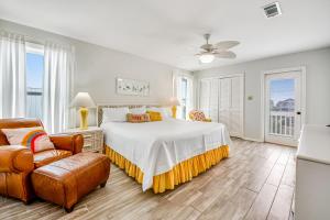 a white bedroom with a bed and a chair at The Flip Side by Meyer Vacation Rentals in Gulf Shores