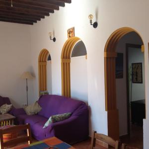 sala de estar con sofá púrpura y 3 arcos en Cortijo Los Flamencos, en Cabo de Gata