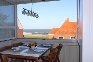 a dining room table with chairs and a large window at Ferienwohnung Ostseeglück, Schönberger Strand, Meerblick in Stakendorfer Strand