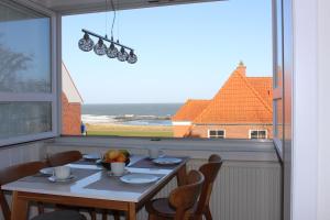 einen Esstisch mit Stühlen und ein großes Fenster in der Unterkunft Ferienwohnung Ostseeglück, Schönberger Strand, Meerblick in Stakendorfer Strand