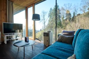 a living room with a blue couch and a large window at Design Apartment mit Naturblick in Bregenz