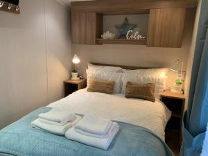 a bedroom with a bed with towels on it at Cosy, coastal themed Holiday Home, Rockley Park, Poole, Dorset in Poole