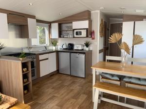 a large kitchen with white cabinets and a wooden floor at Cosy, coastal themed Holiday Home, Rockley Park, Poole, Dorset in Poole