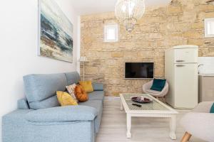 sala de estar con sofá azul y pared de piedra en Allo Apartments Amargura Centro Loft, en Jerez de la Frontera