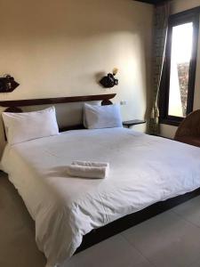 uma grande cama branca com uma toalha branca em Siwasom Resort Sakon Nakhon em Sakon Nakhon