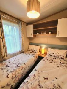 two twin beds in a bedroom with a window at Discover, Relax, Enjoy - All-Round Luxury Lodge in Carlisle