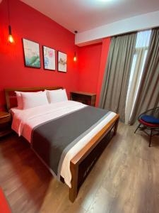 - une chambre avec un grand lit aux murs rouges dans l'établissement Hotel Linge, à Tbilissi