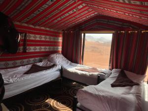 a room with three beds in it with a window at Wadi Rum Starlight Camp in Wadi Rum