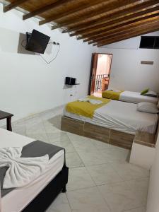 1 dormitorio con 2 camas y TV en la pared en HOTEL BRISAS, en Medellín