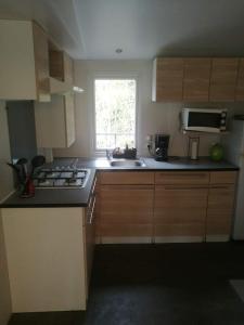 a kitchen with a stove and a sink and a window at la dune blanche in Camiers