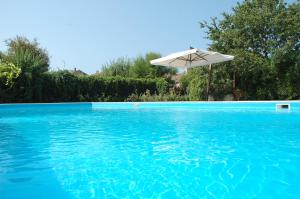 帕埃斯圖姆的住宿－Azienda Agrituristica Seliano，一个带遮阳伞和蓝色海水的游泳池