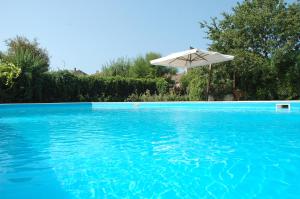 a swimming pool with an umbrella and blue water at Azienda Agrituristica Seliano in Paestum