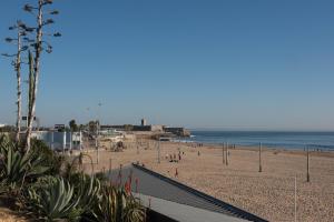 a beach with people on the sand and the ocean at Inesquecível estadia na praia de Carcavelos in Carcavelos