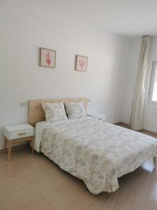 a white bedroom with a bed and two night stands at Apartamento O Serrano in Finisterre
