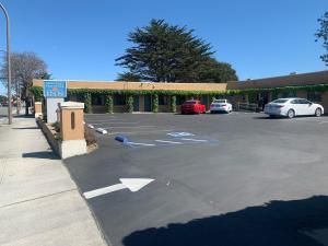 a parking lot with cars parked in front of a building at Monterey Oceanside Inn in Monterey