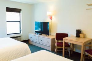 a hotel room with a bed and a desk and a television at Two Sunsets Hotel in Panguitch