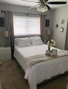 1 dormitorio con 1 cama blanca y ventilador de techo en Sweet dreams private room across from the Hard Rock Casino, en Tampa
