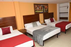 Habitación de hotel con 2 camas con sábanas rojas y blancas en Hotel Kai Soledad Atlántico, en Soledad