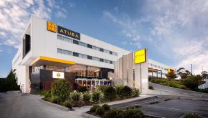 a large white building with a yellow sign on it at Atura Dandenong in Dandenong