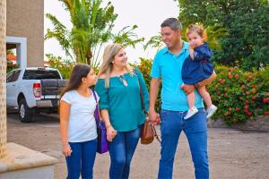 una familia de tres caminando por una calle en Hotel Del Rio, en Navojoa