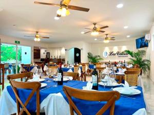 a dining room with blue tables and chairs and ceiling fans at Hotel Boketto in Tuxpan de Rodríguez Cano