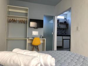 1 dormitorio con 1 cama y 1 silla amarilla en Kalug - Apt Studio em Guest House na Praia do Sul, en Ilhéus