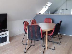 a dining room table with red chairs and a television at Three-Bedroom Holiday home in Vestervig 14 in Vestervig