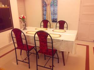 a dining room table with four red chairs and a white table at Fort Garden Residency in Cochin