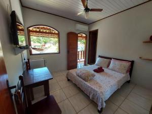 a bedroom with a bed and a table and window at Pousada Flor da Manhã in Sana