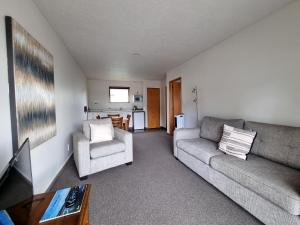 ASURE Highpark Motor Inn في غرايموث: غرفة معيشة مع أريكة وكرسي