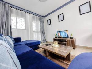 un soggiorno con divano blu e TV di Kyoto 2BR1B a Kampala