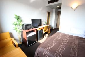 a bedroom with a bed and a desk with a tv at HOTEL LiVEMAX BUDGET Utsunomiya in Utsunomiya