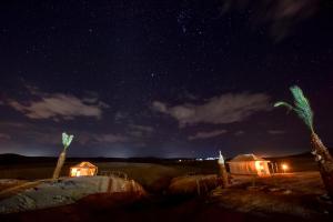 uma vista nocturna para um deserto com estrelas e palmeiras em Agafay Pearl Camp Marrakech em Marrakech