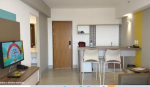 a living room with a kitchen with a bar with white chairs at Enjoy Olímpia Park Resort in Olímpia
