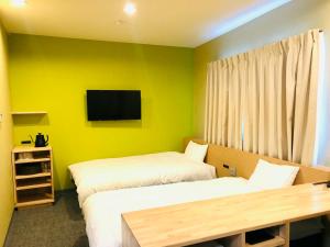 een kamer met 2 bedden en een tv aan de muur bij Hotel Takasago in Kochi