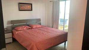 a bedroom with a bed with red sheets and a window at Villa en Ibiza Residence II, disfruta en familia in Río Hato
