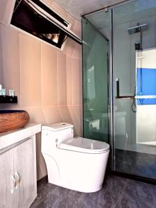 a bathroom with a toilet and a glass shower at Ming Sha Mountain Wild Hostel in Dunhuang