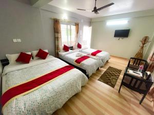 una camera con 2 letti con cuscini rossi di Harvest Moon Guest House a Pokhara