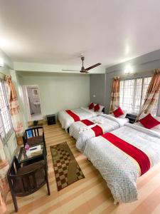 a bedroom with three beds and a ceiling fan at Harvest Moon Guest House in Pokhara