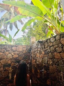 une femme assise à côté d'un mur de pierre dans l'établissement Mango Tree House, à Uda Walawe