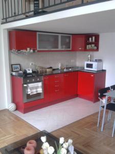 ブダペストにあるSushi Apartmanのキッチン(赤いキャビネット、コンロ付)
