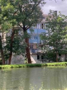 un bâtiment avec un arbre devant une masse d'eau dans l'établissement Le « studio sur la Neste » dans le centre d’Arreau, à Arreau