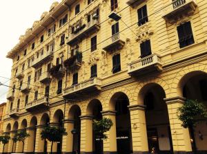 a large yellow building with arches and windows at Lungomare Rooms & Charme in La Spezia