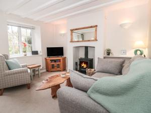 ein Wohnzimmer mit einem Sofa und einem Kamin in der Unterkunft Jasmine Cottage in Axminster